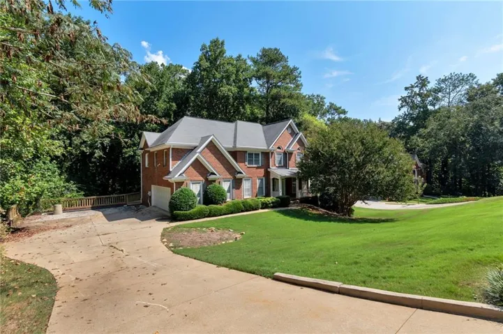 Brick exterior with white trim, a gabled roofline, and an attached garage