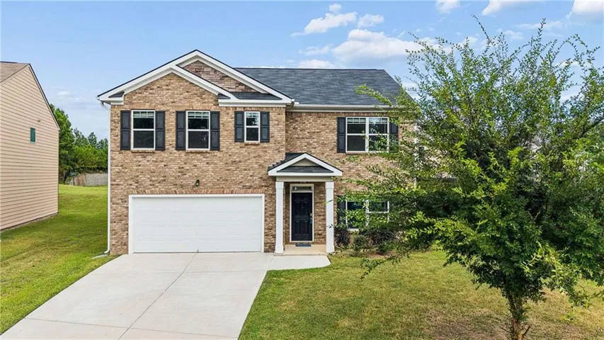 Brick facade with gabled roof lines, attached two-car garage, and a concrete driveway