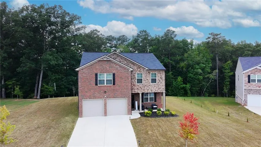 Two-story home featuring a brick and stone facade, a dark shingle roof, and a two-car garage