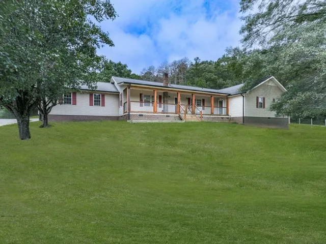 Expansive front yard with a pitched roof, front porch featuring wood columns, wood railing, and a stone foundation