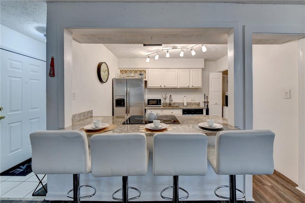 Kitchen with track lighting, stainless steel appliances, a kitchen bar, and white cabinets