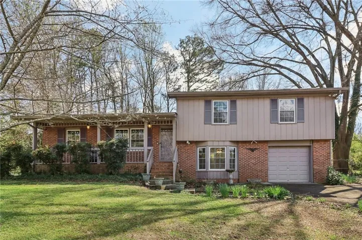 Split level home with brick siding, a garage, and a front yard