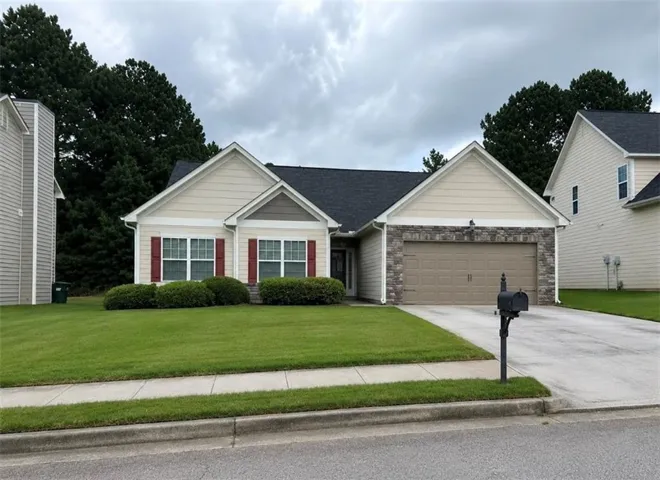 Exterior featuring a dark shingle roof, beige siding, stone-front accents, and an attached two-car garage