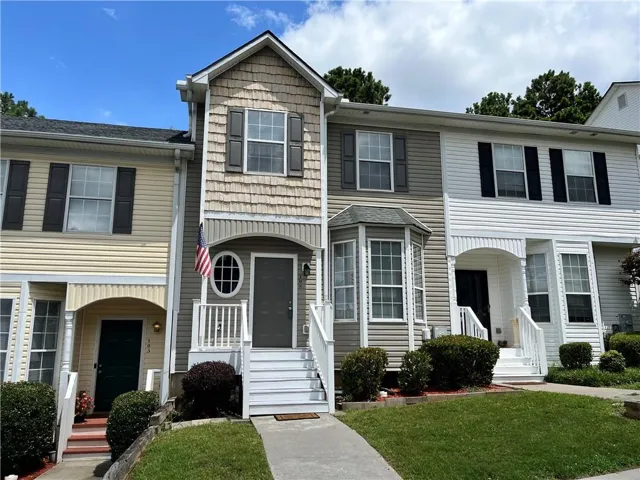 Townhome exterior featuring a bay window, a round oval window, an arched entryway, shingle-style siding, and traditional horizontal siding