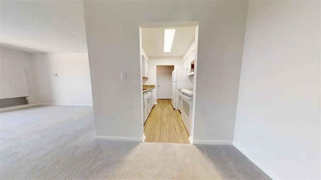 Kitchen featuring white cabinetry, light colored carpet, white appliances, and open floor plan