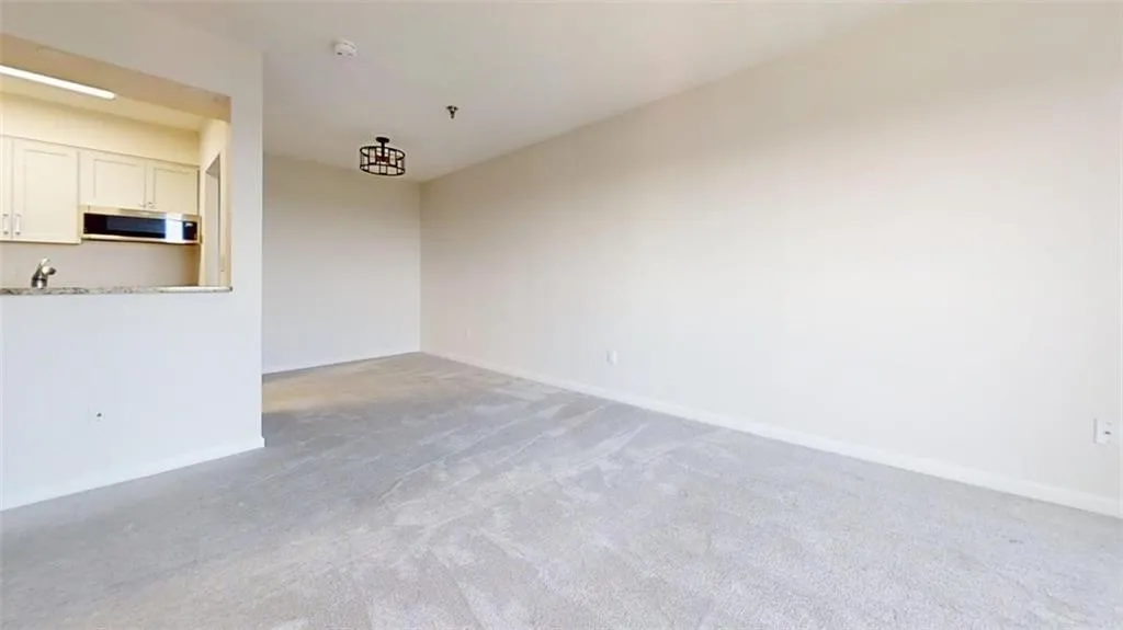 Unfurnished living room with light colored carpet and baseboards