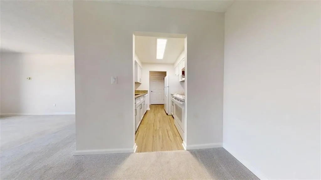 Hallway with light carpet and baseboards