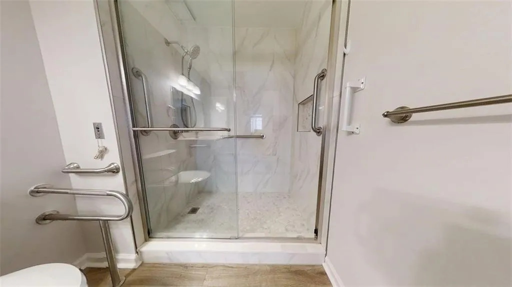 Full bathroom with toilet and a marble finish shower