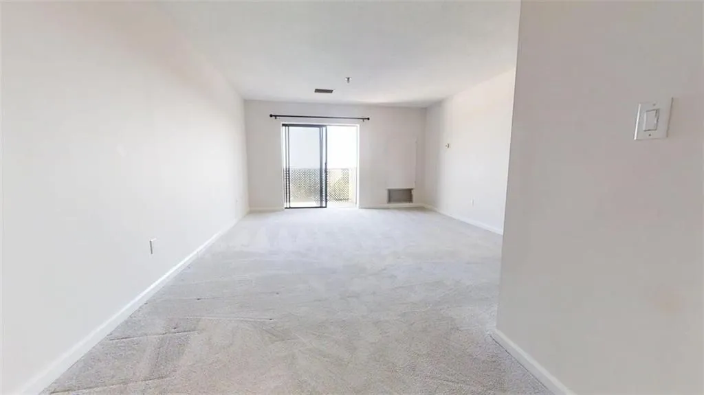 Empty room with light colored carpet and baseboards