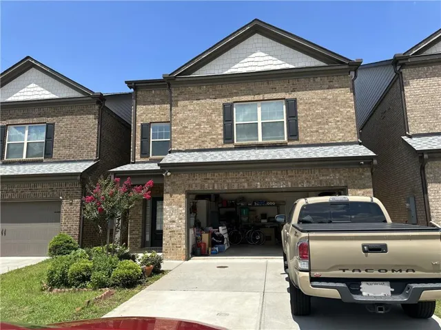 Brick and siding exterior featuring dark shutters, a two-car garage, and a concrete driveway