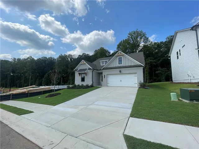 White brick exterior with gray siding accents, attached two-car garage, concrete driveway, and manicured lawn