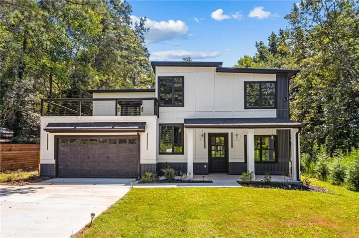Contemporary exterior with a flat roofline, covered entry, attached garage, upper-level balcony, and mature tree surroundings