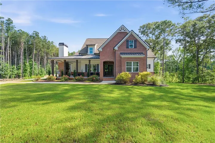 Brick and siding exterior featuring a covered porch with dark columns