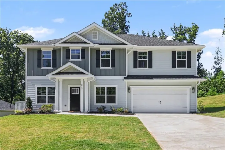 Two-story exterior with light blue and grey siding, dark shutters, an attached two-car garage, concrete driveway, and covered front entry