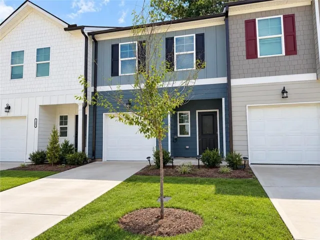 Two-story townhome with distinct siding styles and individual garage access