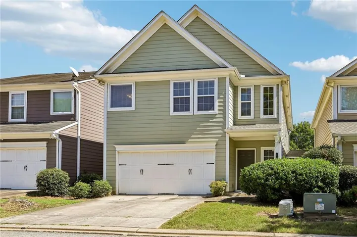 Two-story exterior with siding, attached two-car garage, established front landscaping, and a concrete driveway