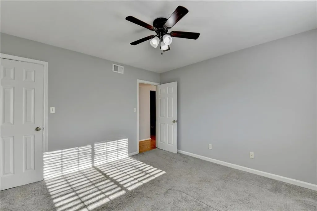 Unfurnished bedroom with light colored carpet and ceiling fan