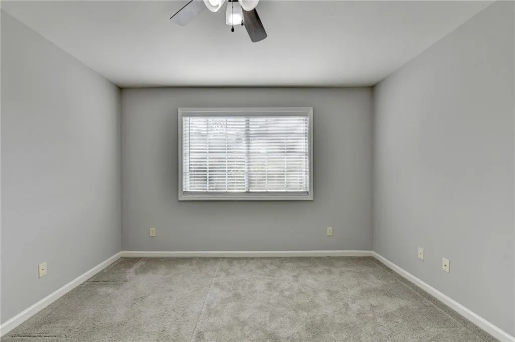 Empty room featuring ceiling fan and light carpet