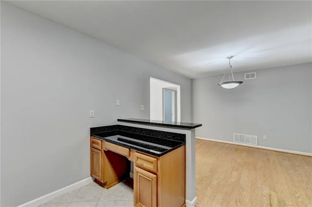 Kitchen with a peninsula, hanging light fixtures, dark stone counters, and light wood finished floors