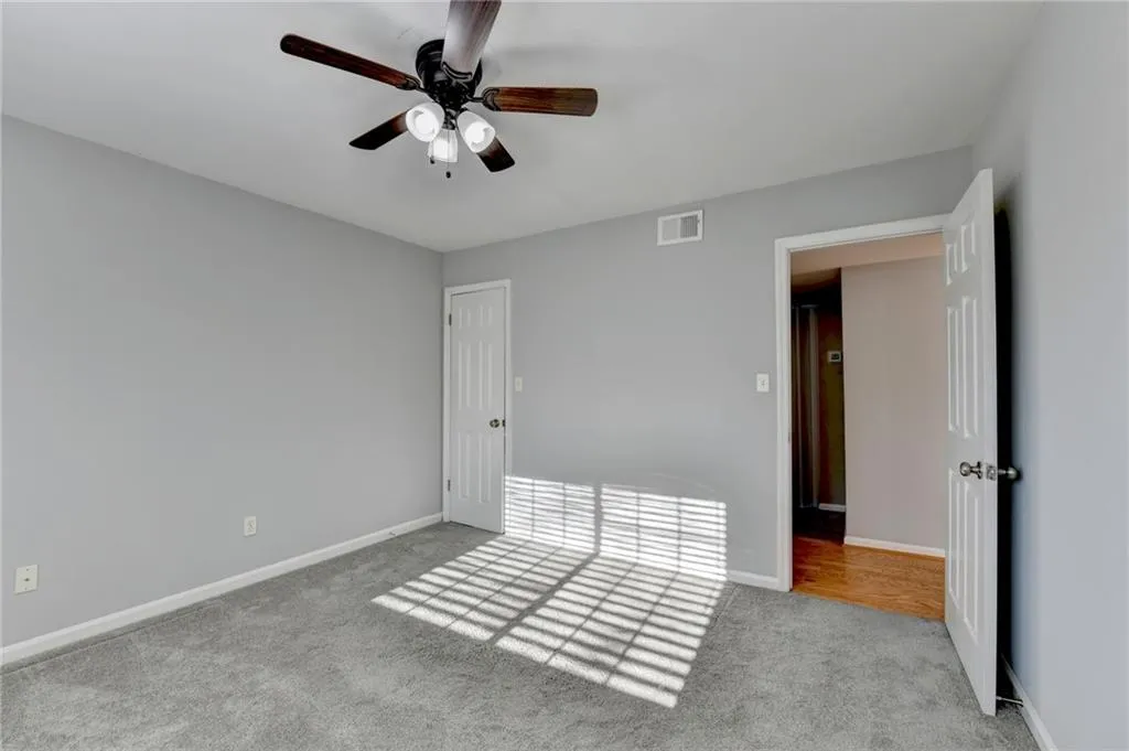 Unfurnished bedroom featuring light colored carpet, ceiling fan, and a closet