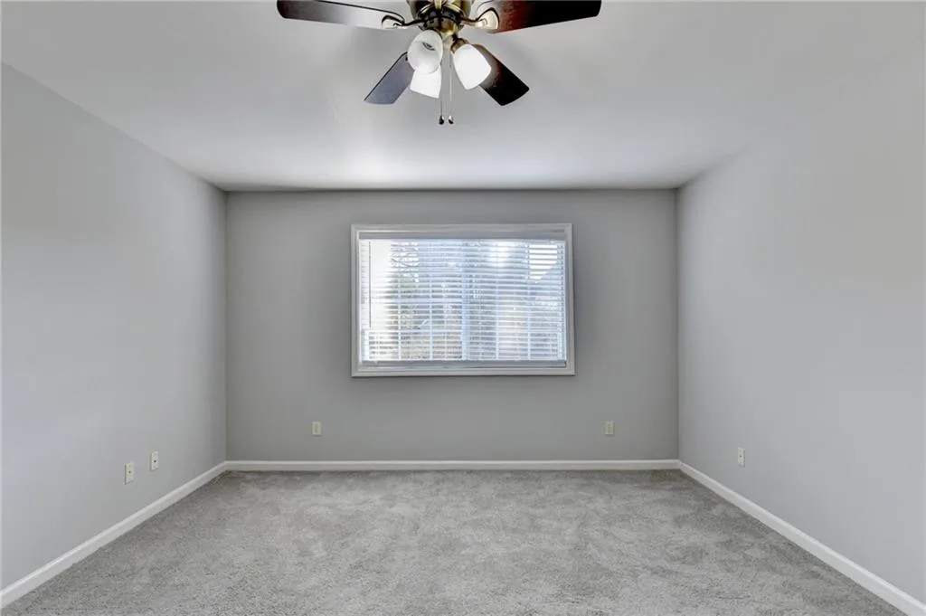 Carpeted spare room with ceiling fan and baseboards