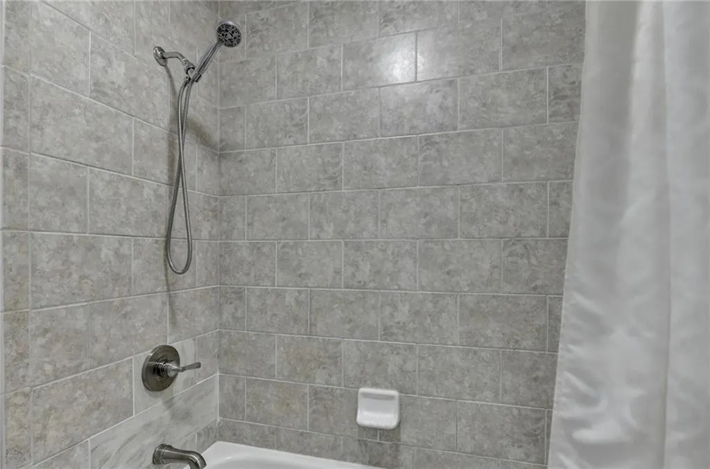 Bathroom view of shower / bath combination with curtain