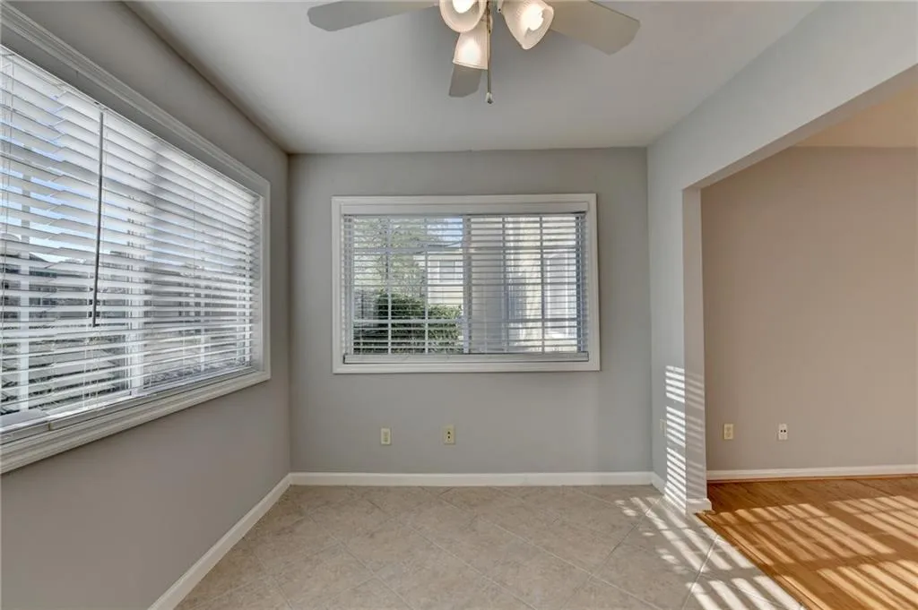 Empty room with a ceiling fan and light tile patterned flooring