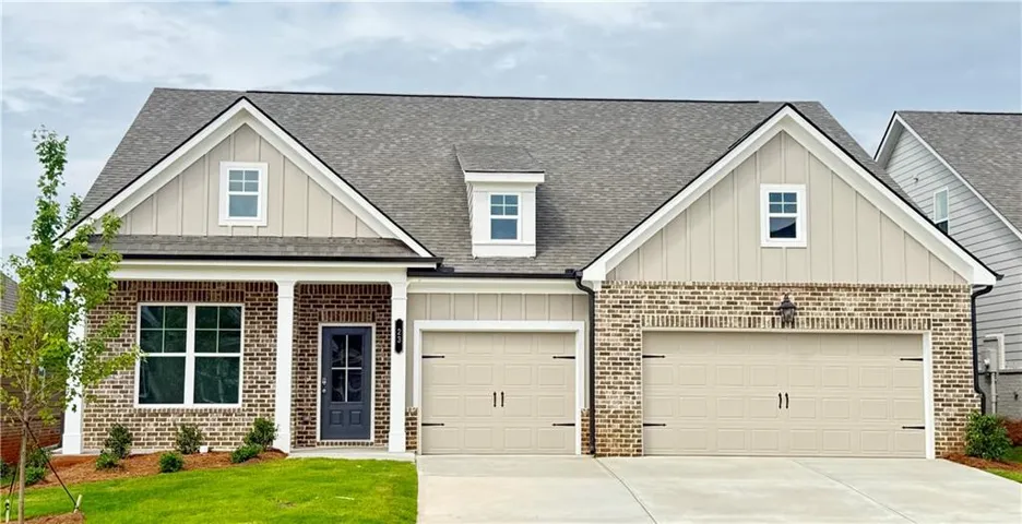 Contemporary home featuring a brick and siding exterior, a two-car garage, a covered front entry with columns, and dormer windows