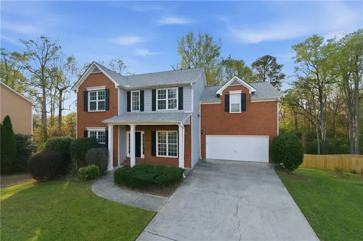 Traditional home with concrete driveway, a porch, a shingled roof, and brick siding