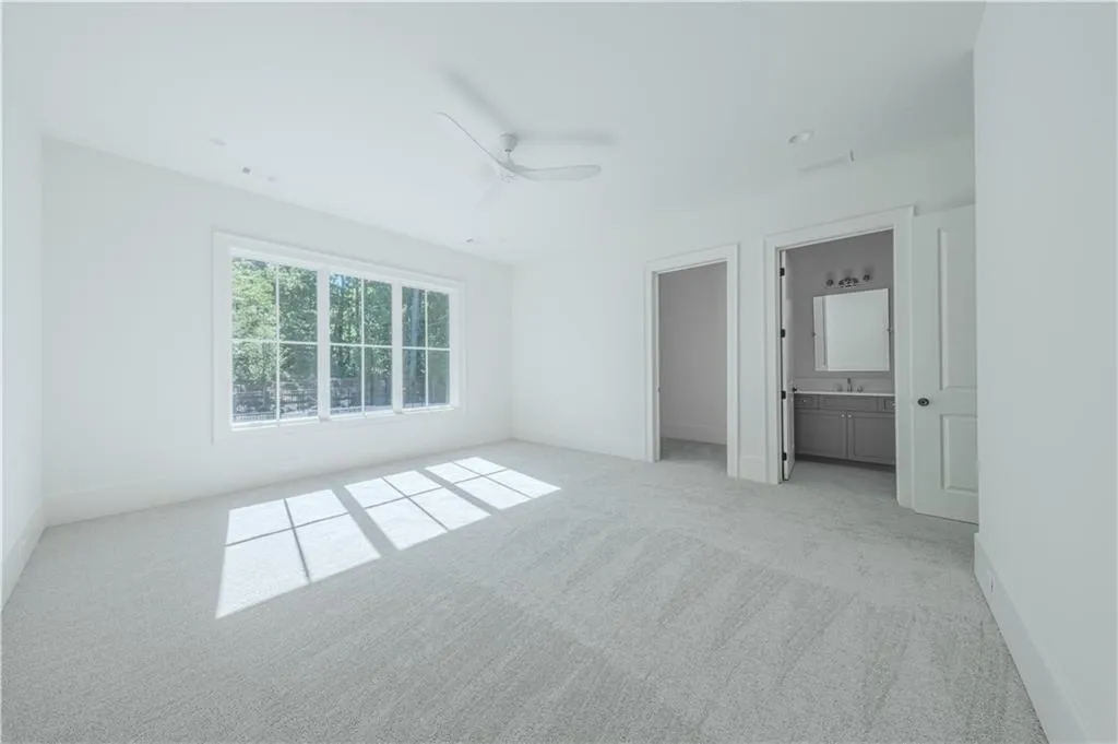 Unfurnished bedroom with ensuite bathroom, sink, ceiling fan, and light colored carpet