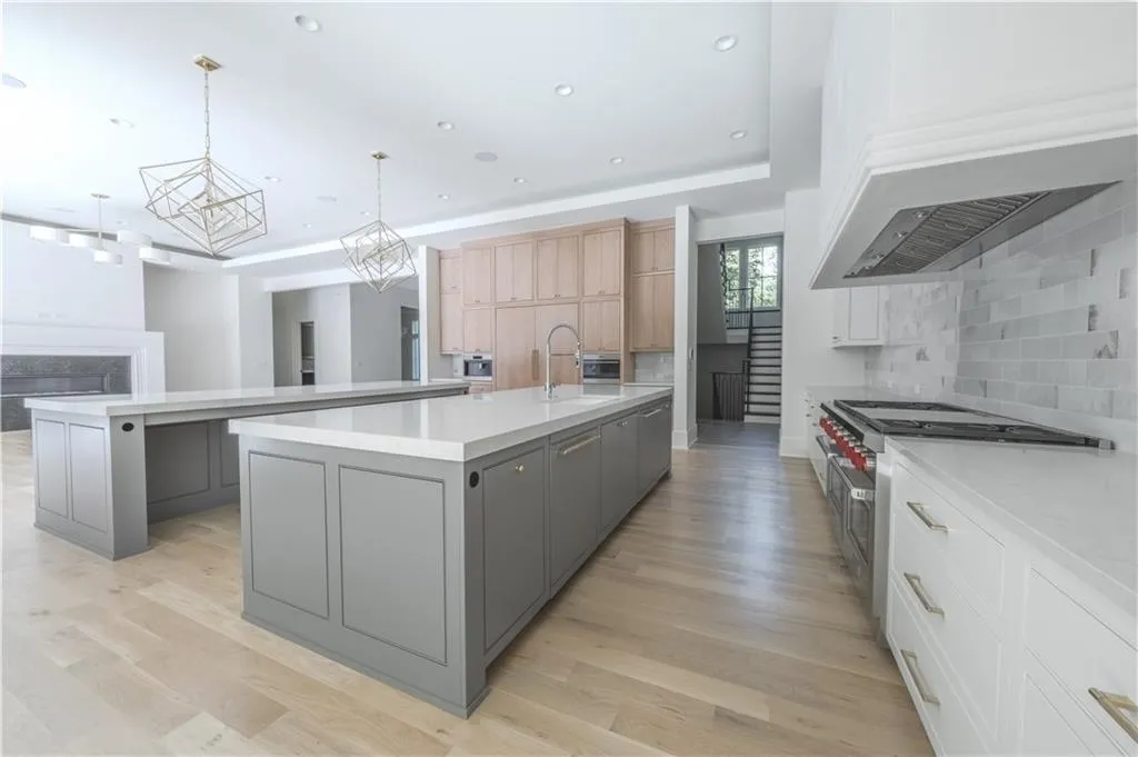 Kitchen with white cabinetry, tasteful backsplash, an island with sink, decorative light fixtures, and gray cabinets