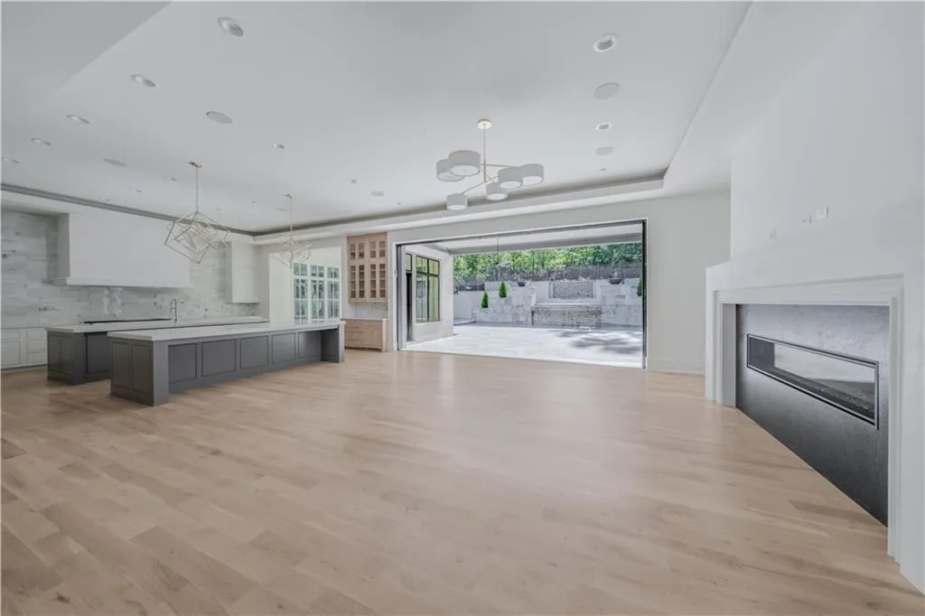 Unfurnished living room featuring an inviting chandelier, a tray ceiling, and light hardwood / wood-style flooring