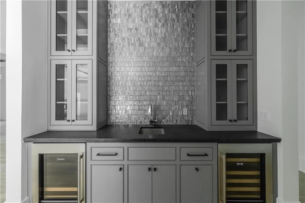 Bar featuring backsplash, white cabinetry, sink, and beverage cooler