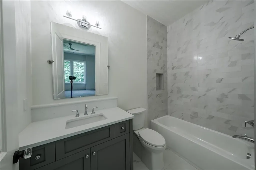 Full bathroom featuring vanity, ceiling fan, toilet, and tiled shower / bath