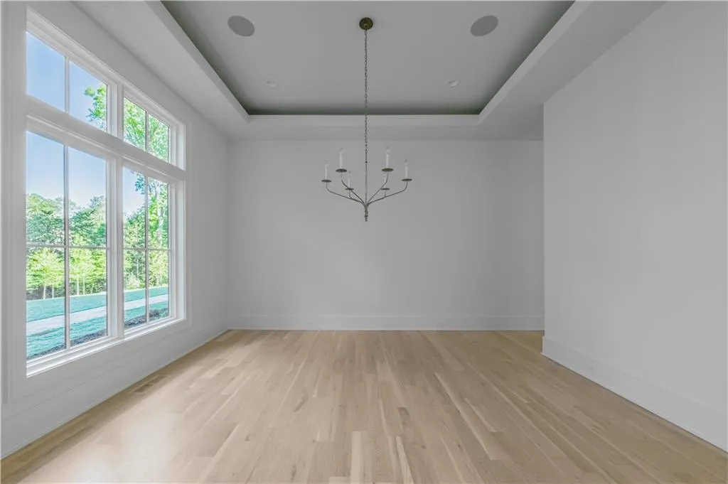 Unfurnished dining area featuring a chandelier, light hardwood / wood-style floors, and a tray ceiling