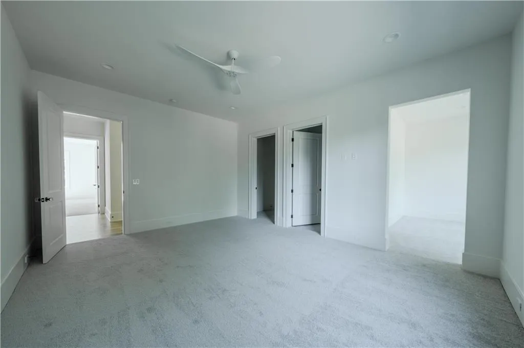 Unfurnished bedroom with light colored carpet and ceiling fan