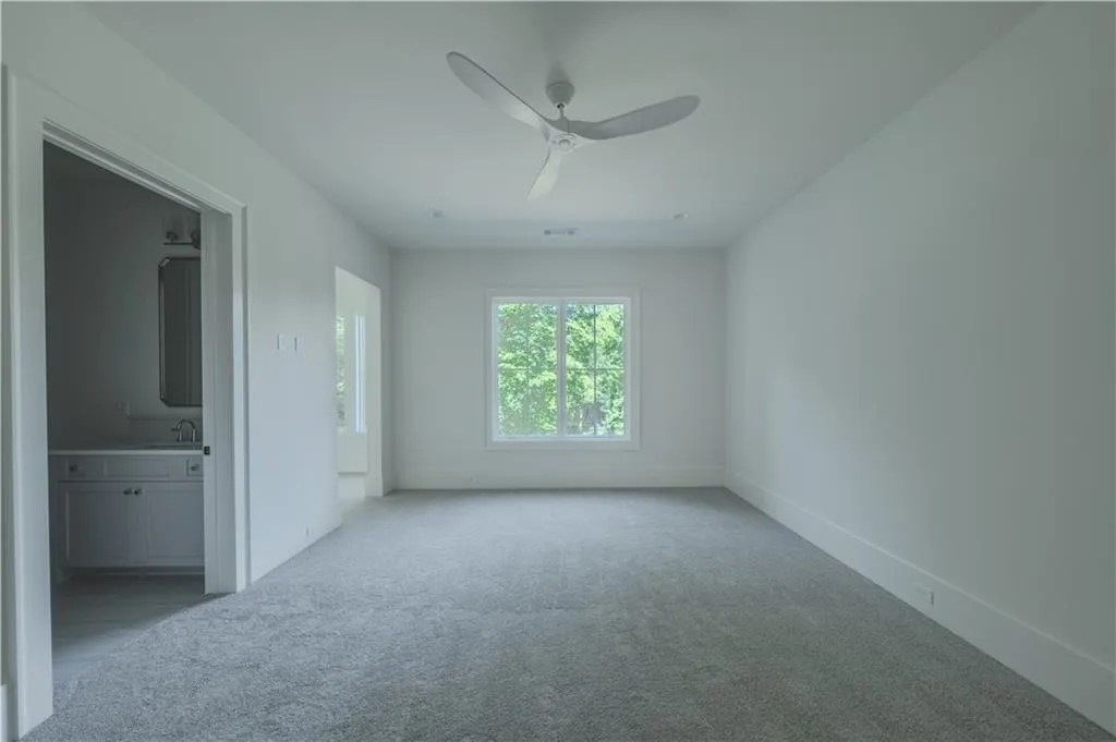 Carpeted spare room featuring ceiling fan and sink