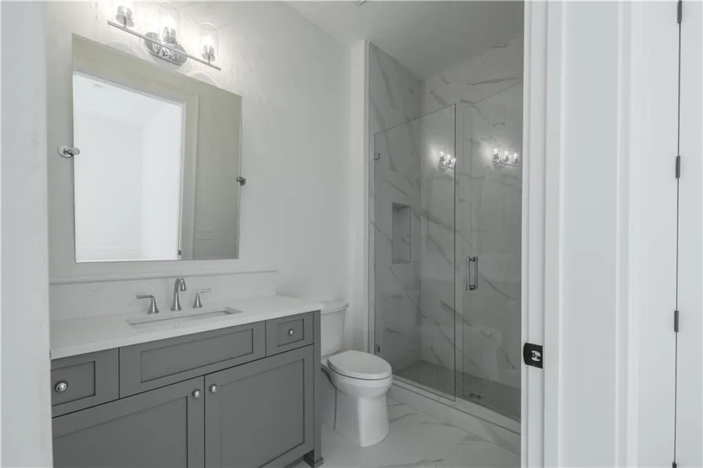 Bathroom with toilet, an enclosed shower, and vanity