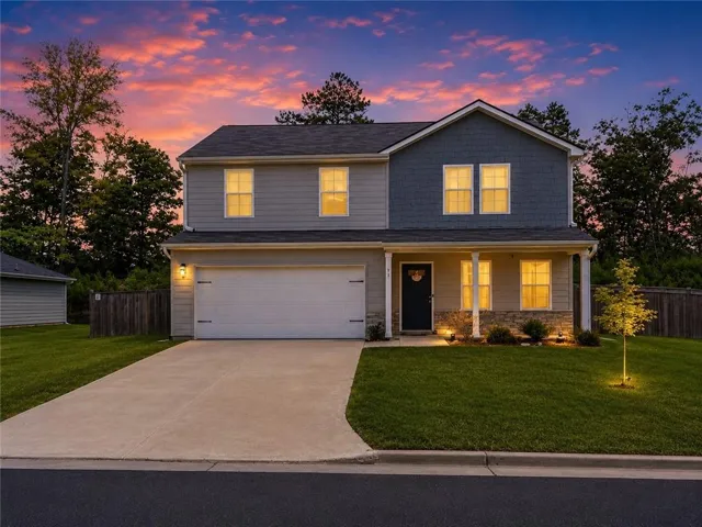 Two-story residence featuring a covered front entry with stone veneer accents, a prominent two-car garage, and a concrete driveway