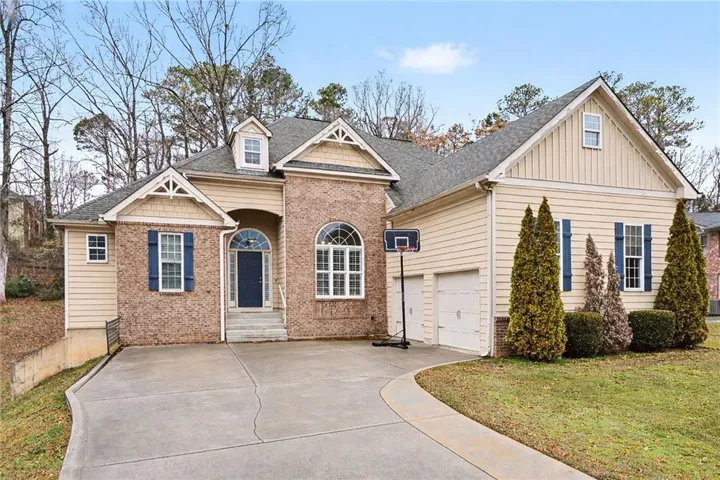 Brick and siding exterior featuring a covered front entry with an arched transom, a two-car garage, and a concrete driveway