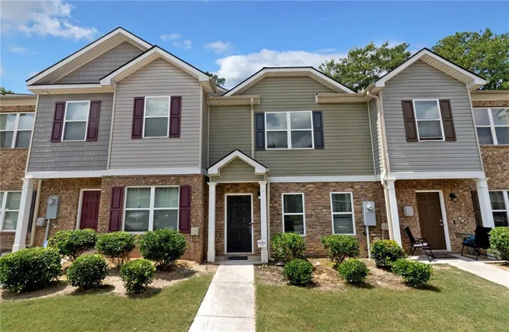 Townhome exterior featuring brick and siding facade, gabled roofs, and manicured landscaping