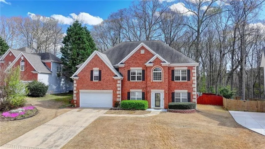 Brick exterior with white trim, two-car garage, front entry door, and arched window accent