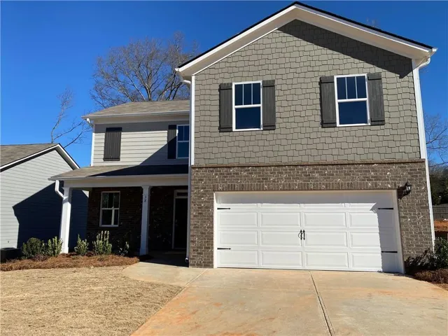 View of front of house with a porch, driveway, brick siding, and an attached garage