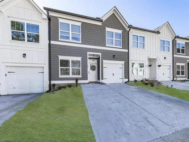 Modern townhome exterior featuring a two-tone facade with white board-and-batten siding and gray horizontal siding