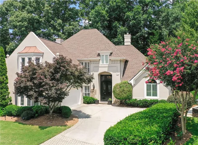 Street view of structure with side entry garage, envied front iron door, multiple window styles and brand new architectural roof and mature landscape.