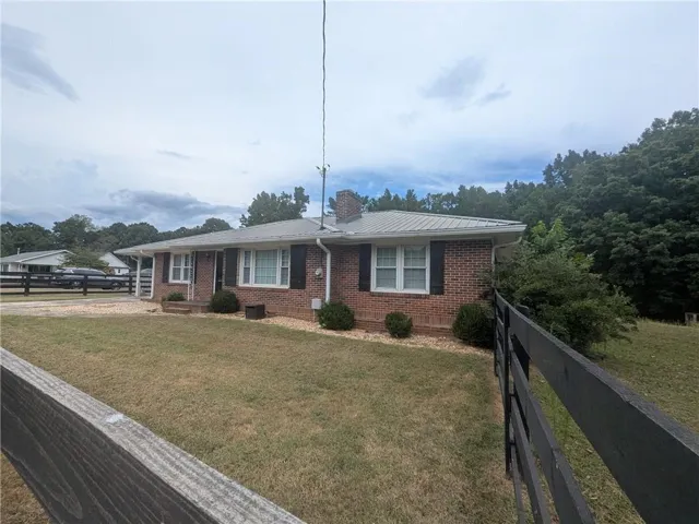 Brick exterior with a metal roof, contrasting black shutters, and a wood fence