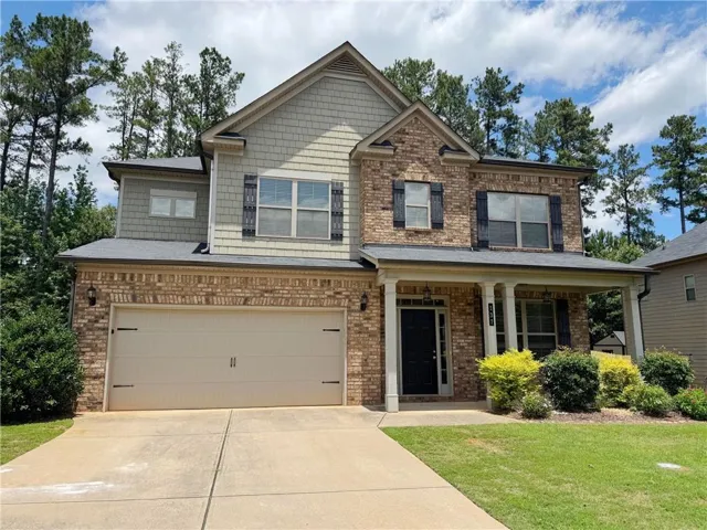 Traditional two-story exterior featuring a brick and shake facade, covered front porch, and an attached two-car garage