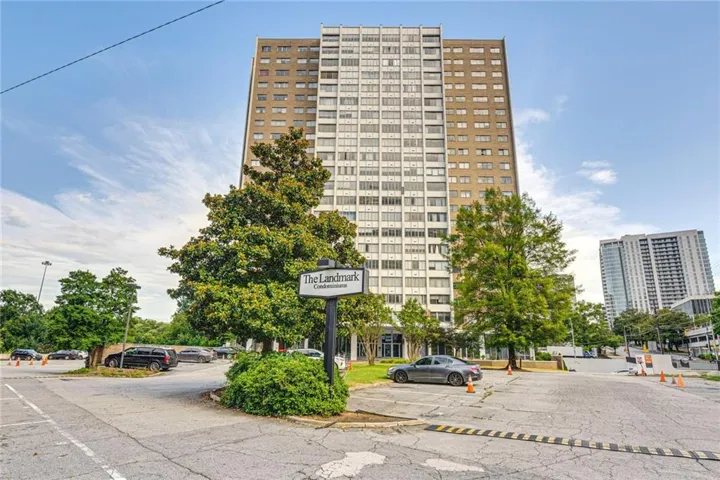 High-rise residential building featuring a multi-story facade, prominent signage, and a circular driveway with mature landscaping