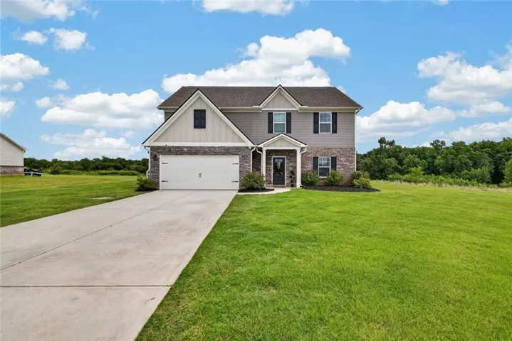 Two-story residence featuring a combination of brick and siding, an attached two-car garage, a concrete driveway, and a spacious front lawn
