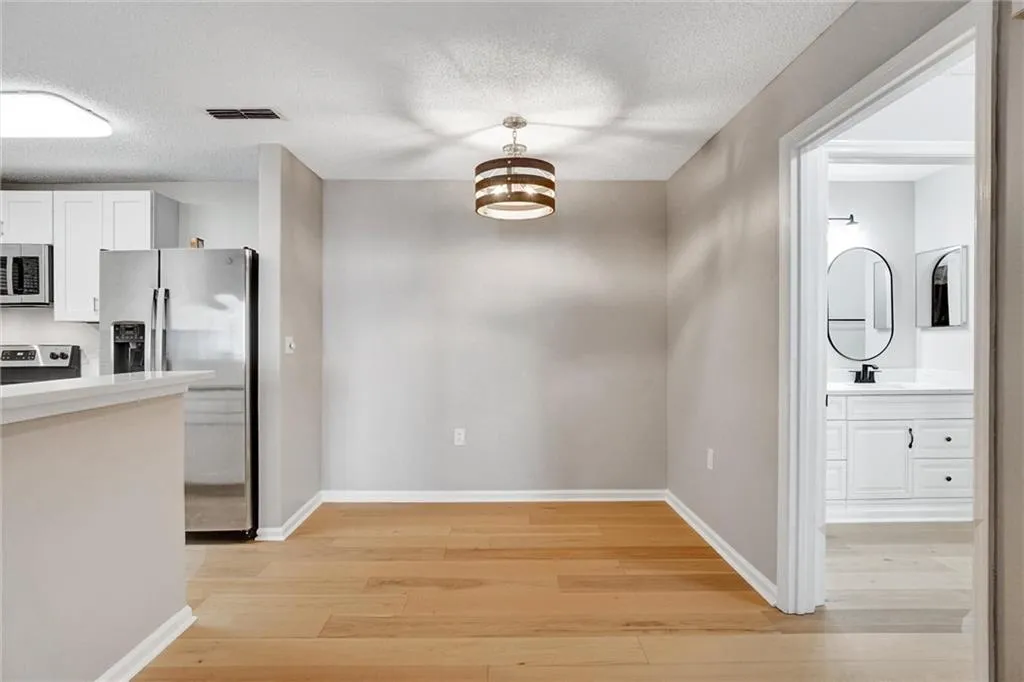 Unfurnished dining area with light wood-type flooring, a textured ceiling, and a chandelier